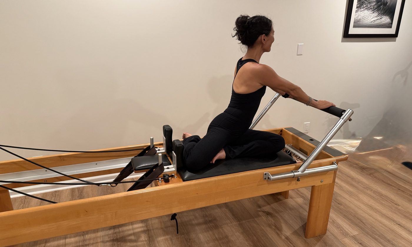 Dr. Moon demonstrating a side bend on the Pilates reformer.